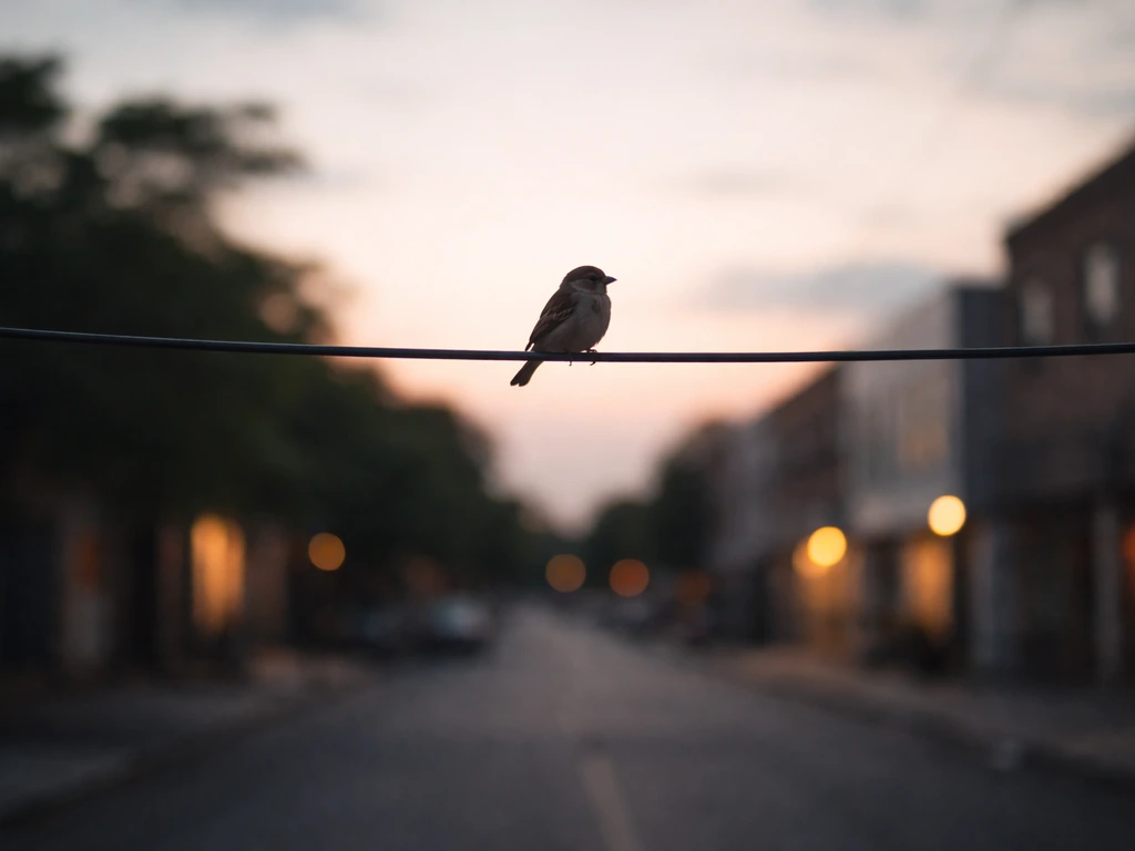 A small bird perched on an overhead wire against a soft evening sky with distant blurred city lights.